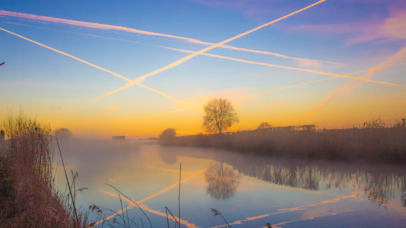 Zonsopkomt in Buurmalsen, het zijn vliegtuigstrepen die de lucht kleuren - Ab Donker
