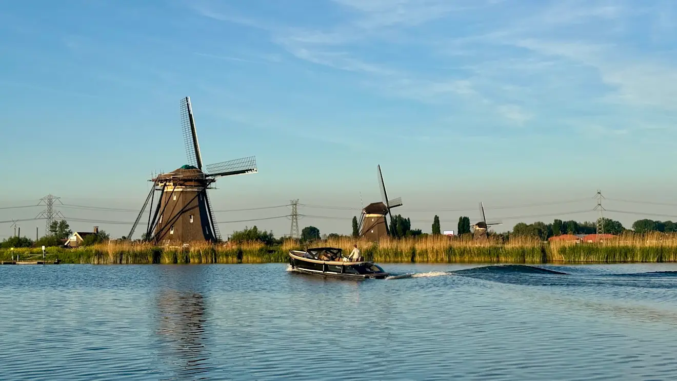 Prachtig beeld van molens en een boot die daar langs vaart - Jolanda Bakker