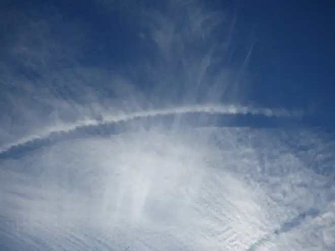 Een contrail (vliegtuigstreep) in een veld met cirrus en cirrocumulus - Foto uit archief