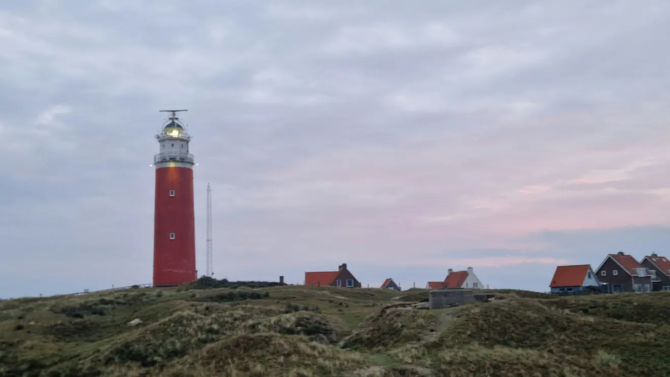 Vroeg zonlicht schijnt oranjekleurig door de wolken boven Texel - Frans Alderse Baas