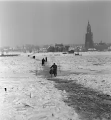 Voetgangers steken bij Rhenen de Rijn over die met een dikke laag ijs bedekt was - Herbert Behrens / Anefo