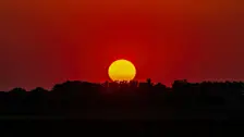 Een rood ondergaande zon, met daarop ook zonnevlekken zichtbaar - Simone Genna